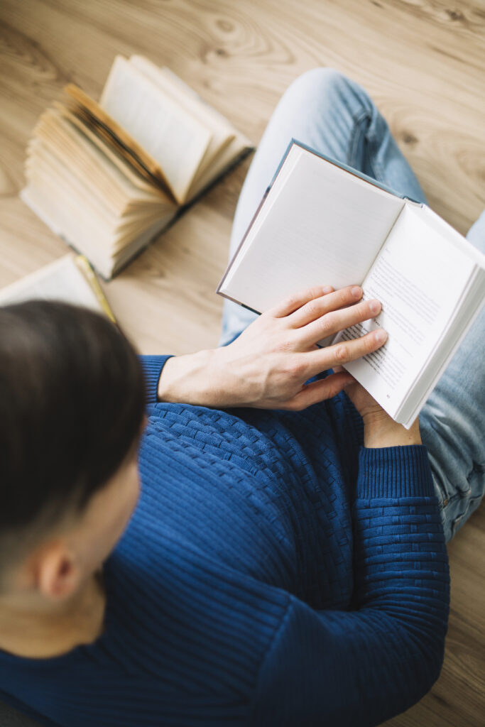 Imagen de varios libros y alguien está leyendo uno
